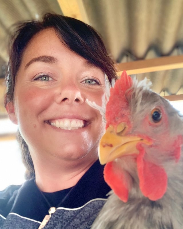 A staff member with a chicken on the farm